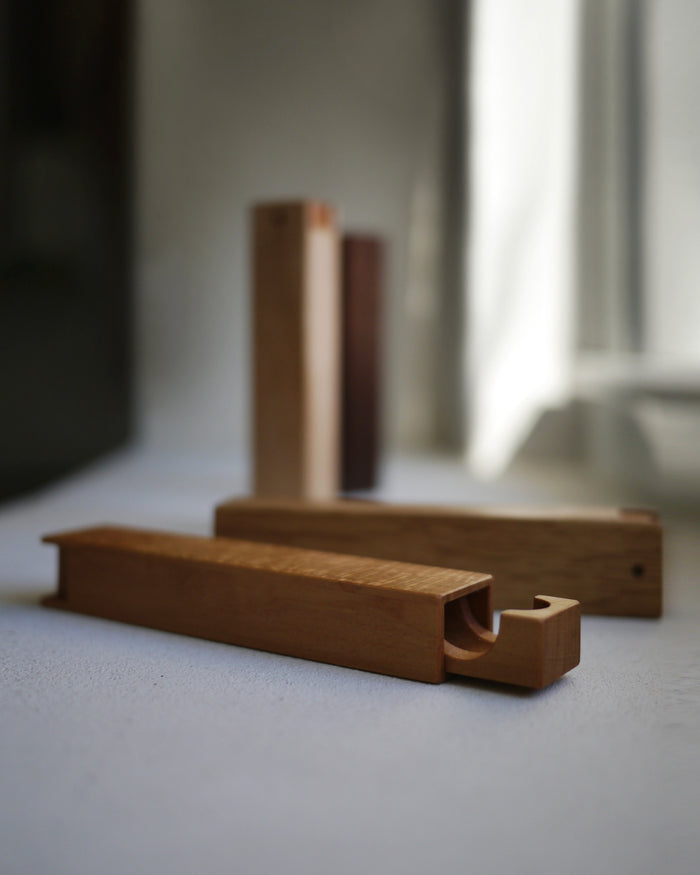 Wooden toothpick cases by Nalata Nalata and Tanno laying on a gray backdrop